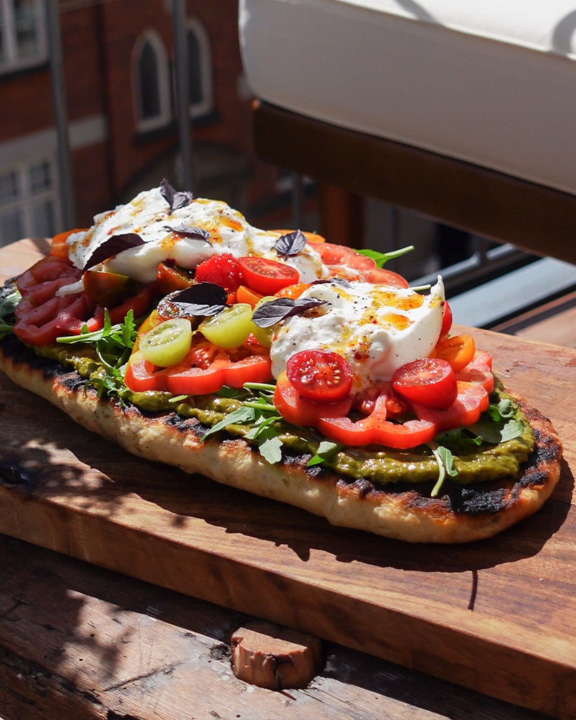 Recipe: Large grilled garlic flatbread with burrata, tomatoes, pesto, and lime-chili honey